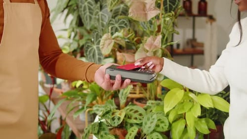 Shopping in Flower Store African American Woman Buying Plants and Paying By Credit Bank Card in