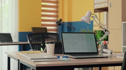 Arbeitsplatz bestehend aus Tischen mit Laptops, Dokumenten und Lampen