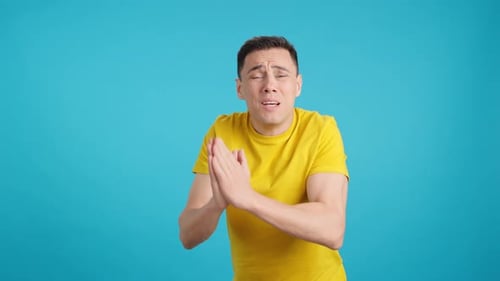 Young Man Pleads with Hands Clasped Together