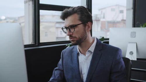 A Professional Man Focused on His Work at a Computer in a Contemporary Office Setting