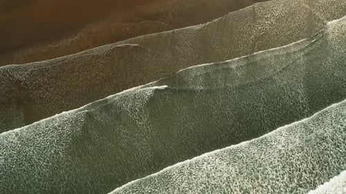 Abstract aerial of ocean waves rolling over sandy beach at Playa Linda Costa Rica