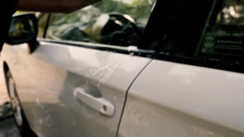 Close up of a male washing a car wearing a black gloves with shampoo and sponge