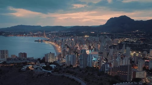 Busy seafront city with skyscrapers and modern buildings next to the ocean. Beautiful orange sunset.