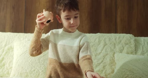 A Child is Saving Coins in a Piggy Bank Shown in Closeup The Child Holds a Pink Piggy Bank Shakes It