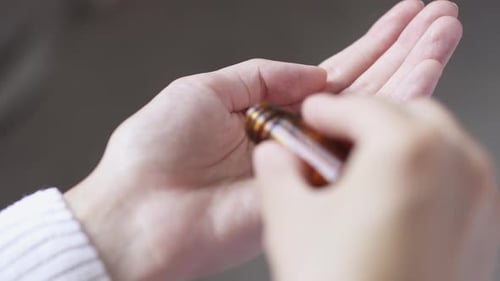 Woman takes and pours pills, vitamins or pain relievers from a glass bottle with pills. Close-up