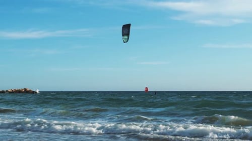 Young active man riding on sea waves on kiteboard at windy day