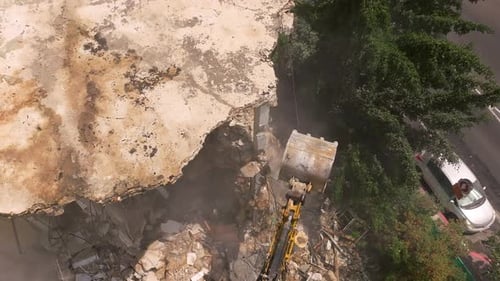 Excavator arm demolishing an old building, Aerial view