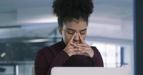 4k video footage of a young businesswoman looking stressed while using a laptop in a modern office