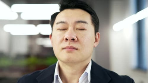 Asian businessman is meditating while sitting at workplace in business office. A man in formal suit