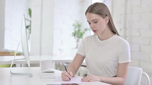 Hardworking Young Woman doing Paperwork in Office