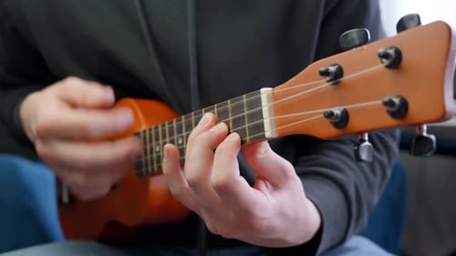 Slow motion view Caucasian male hands play ukulele stringed guitar, music instrument teaching