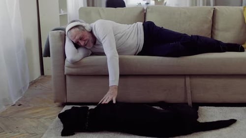 Senior Man Relaxing on Sofa with Dog
