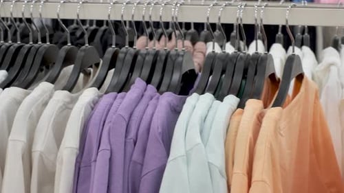 Side view of colorful cotton t-shirts hanging on hanger in a store.