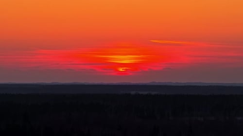 Fiery sunset colors glowing over distant horizon with colorful sky in aerial view