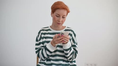 Studio Portrait of Focused Pretty Young Woman Texting Online Message Using Modern Smartphone