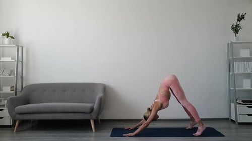 Young Woman Practicing Yoga Downward Dog Position at Home