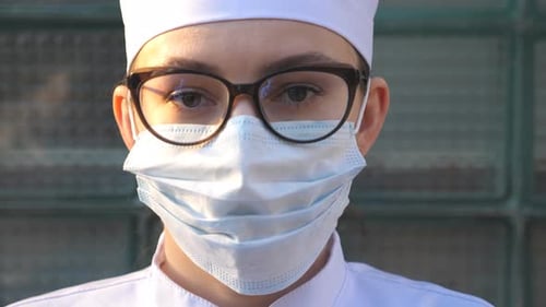 Porträt einer jungen Ärztin mit medizinischer Gesichtsmaske schaut in die Kamera, die eine medizinische Mitarbeiterin trägt