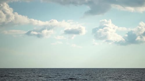 Flauschige Wolken bewegen sich am blauen Himmel über ruhiger See Abstrakte Luft Natur Sommer Ozean Sonnenuntergang Meer und