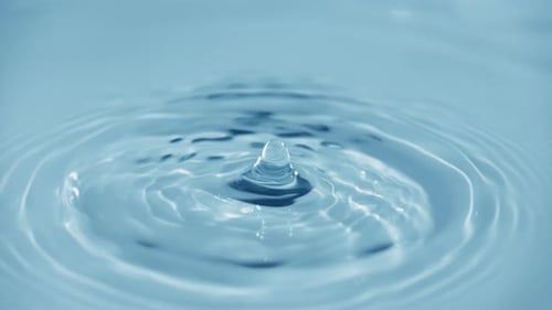 Water Droplets Creating Ripples in Clear Blue Pool