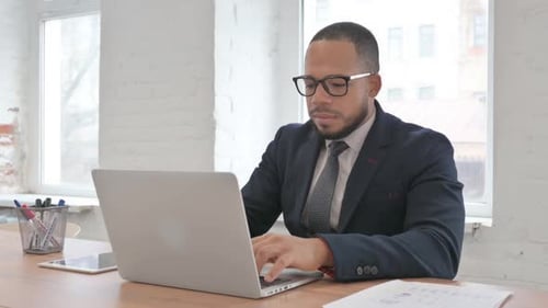 Excited Mixed Race Businessman Celebrating Success on Laptop in Office