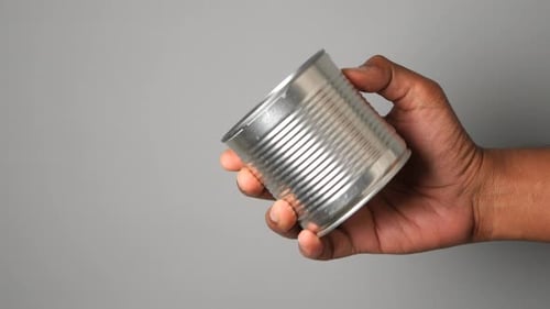 Hand Holding a Metal Can with a Simple Gray Background