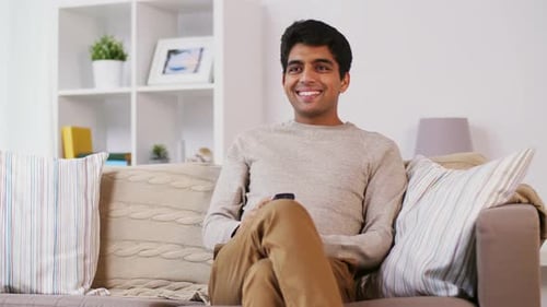 Smiling Man Relaxing on Couch with Remote Control