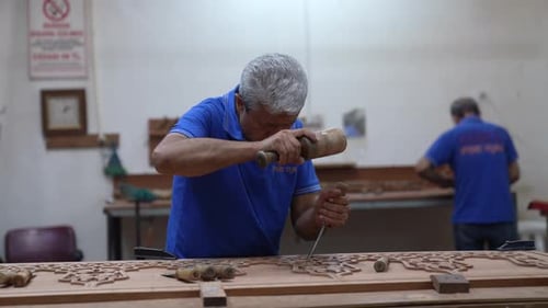 Craftsman Carving Intricate Wood Design with Chisel in Workshop