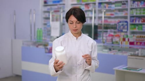Woman Pharmacist with Safety Glasses in Pharmacy