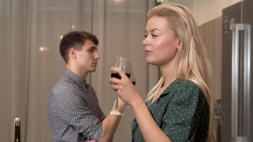 Fröhliches Paar, das in seiner gemütlichen Wohnung mit Wein anstößt und Liebe ausstrahlt