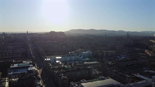 Edinburgh city skyline at sunset with Edinburgh Castle, autumn colors, and distant hills.