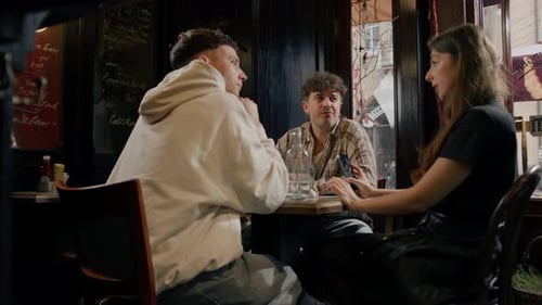 Wide shot - a group of friends chatting at a table in a restaurant, eating a burger and french fries