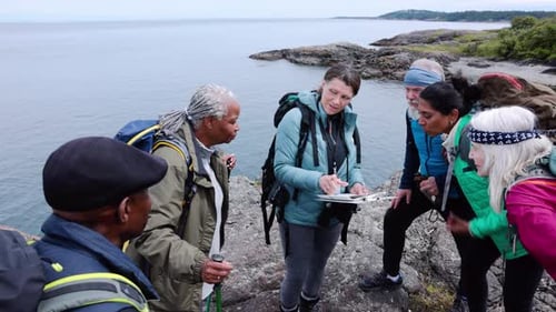 Guide with Board Leading Senior Friends Hing on Ocean Cliff