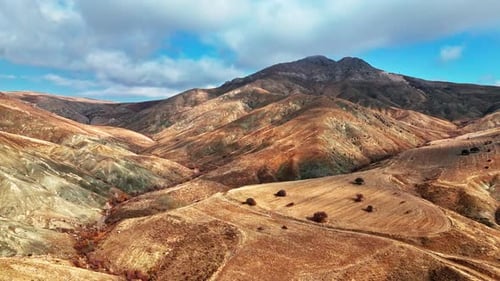 Aerial Views of Lake, Arid Hills and Mountains Under Dramatic Clouds