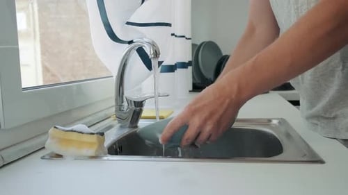 Man Washing Dishes in the Kitchen Sink Male Hands Wash a Dish at Home with Sponge and Soap Daily