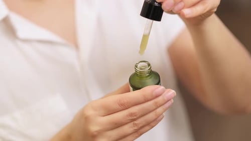 Close Up of Dropper Dispensing Oil into Bottle