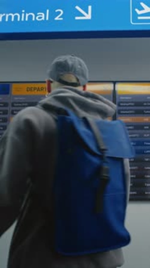 Airport Terminal Passengers with Luggage and Tickets Checking Departures on Digital Departure Board