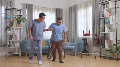 Male Nurse Holding Patient'S Hand Who In A Wheelchair To Stand Up And Walk During A Physical Therapy