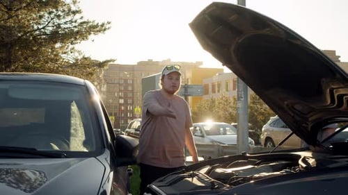 Two Men Look at Car Engine in City