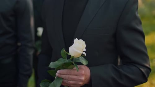 Mourners Holding Roses at an Outdoor Memorial