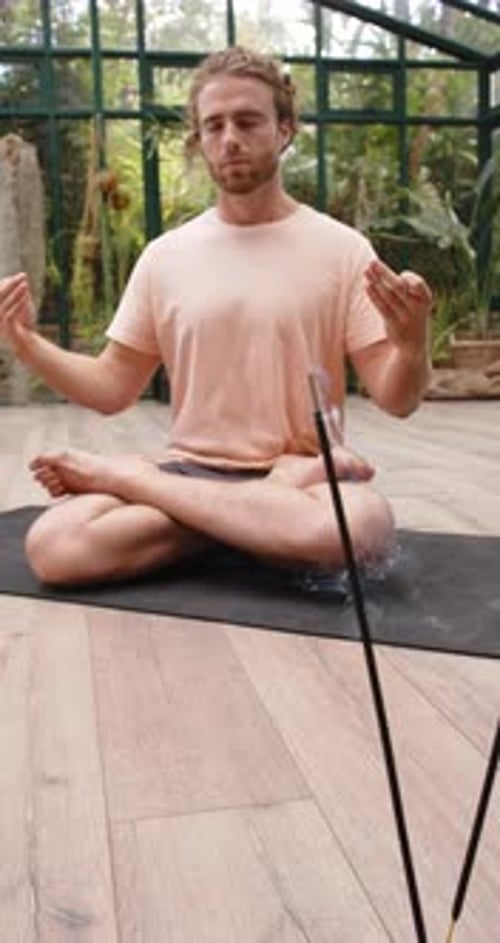 Man Meditating with Incense in a Bright Sunroom