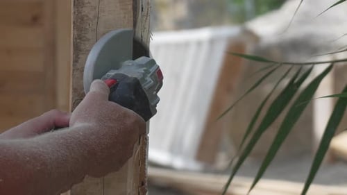 Man Using Saw to Cut Wood Plank