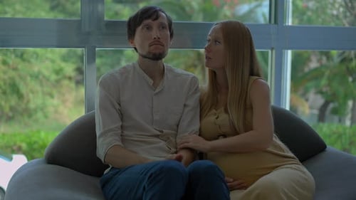 Distressed Man with Pregnant Partner Indoors