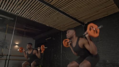 Motivated Sporty Fit Black Man Doing Barbell Squats in Health Club