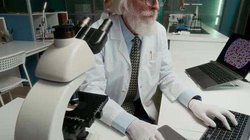 Senior Scientist Works with Microscope in Lab