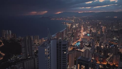 Busy seafront city with modern buildings next to the ocean at dusk.