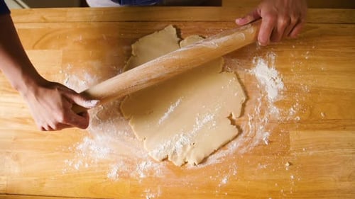 Woman Rolling Dough on a Wooden Counter