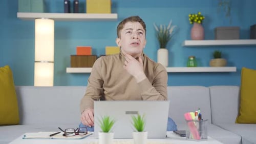 Young Man with Sore Throat Massaging Neck at Home