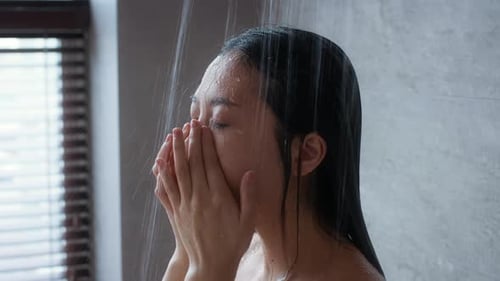 Woman Washing Face in Shower with Eyes Closed