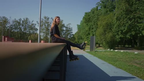 sporty girl after rollerblading rests on the sports ground thoughtful and happy with the street