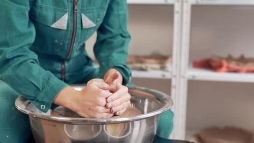 Closeup of hands fixing clay on pottery wheel